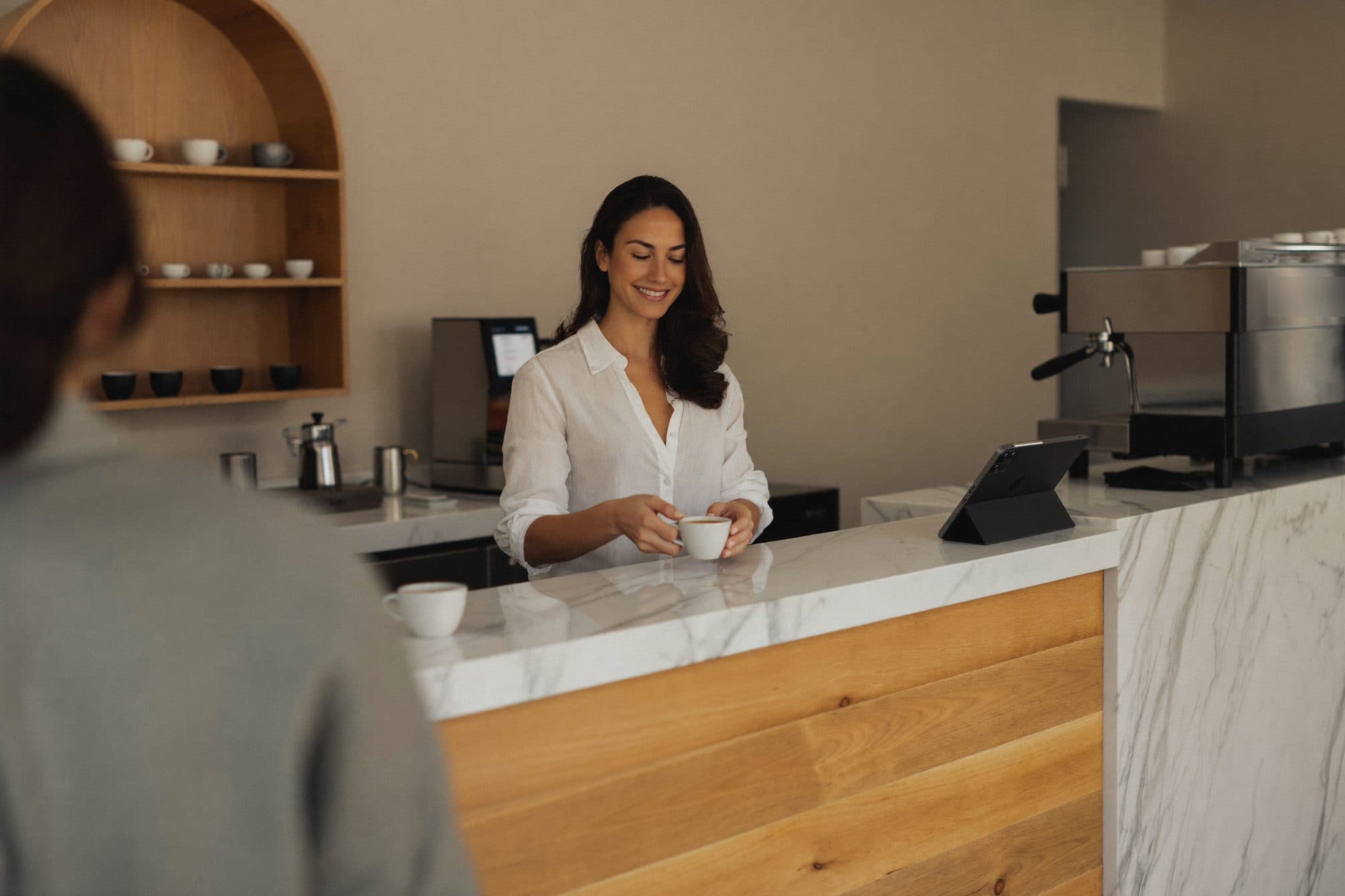 La dueña de una cafetería de especialidad entrega un café en la barra de mármol.