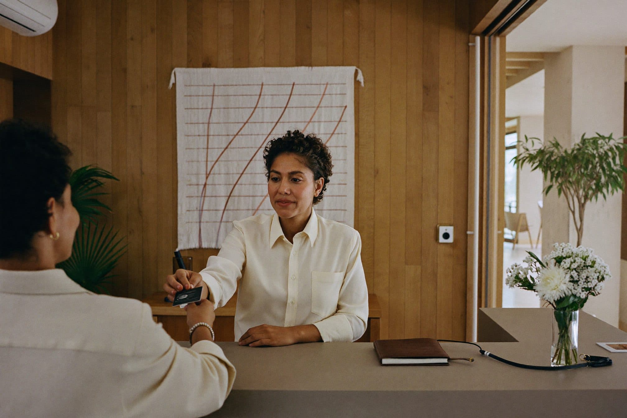 La recepcionista de un hotel boutique le entrega la tarjeta de la habitación a una huésped.